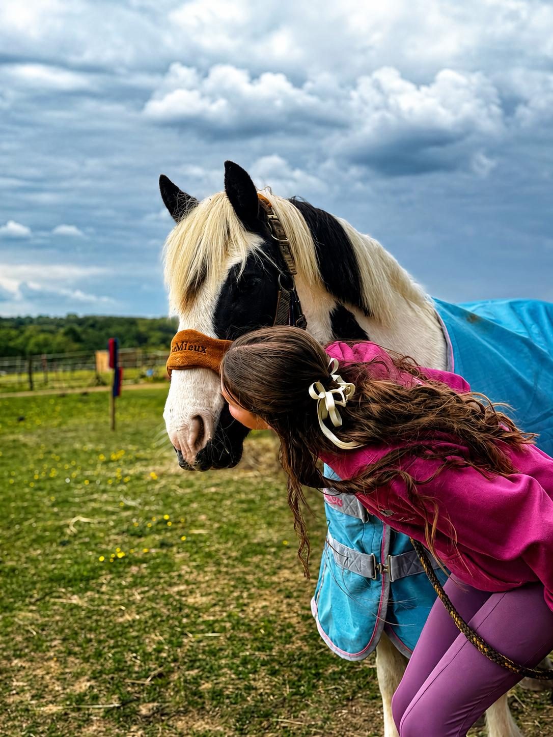 Young rider kissing a piebald cob on the nose